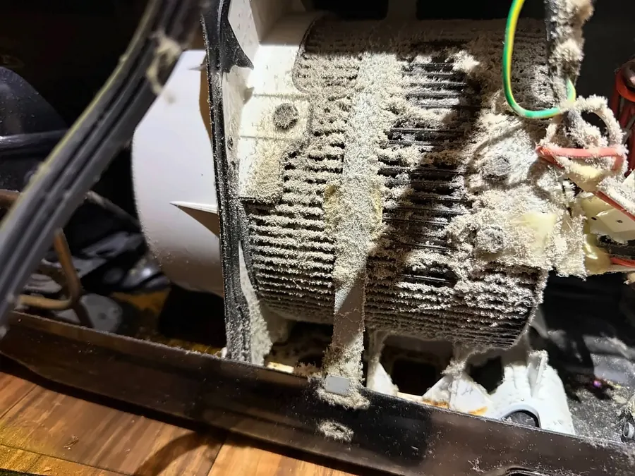 A condenser coil packed with dust, a common reason fridges run warm