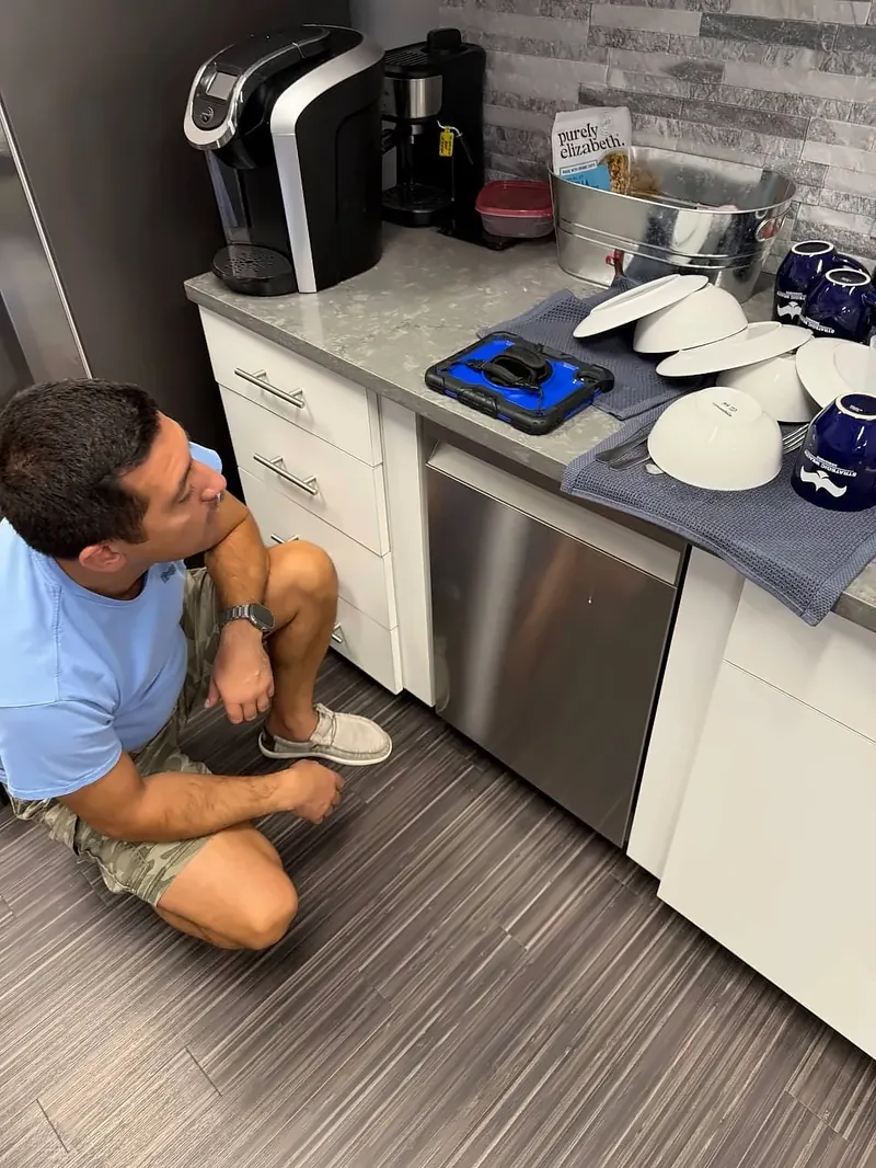 A technician diagnosing a dishwasher on site